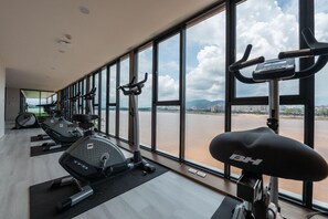 Ein Fitnessstudio mit Trainingsgeräten und großen Fenstern mit Blick auf einen Fluss.