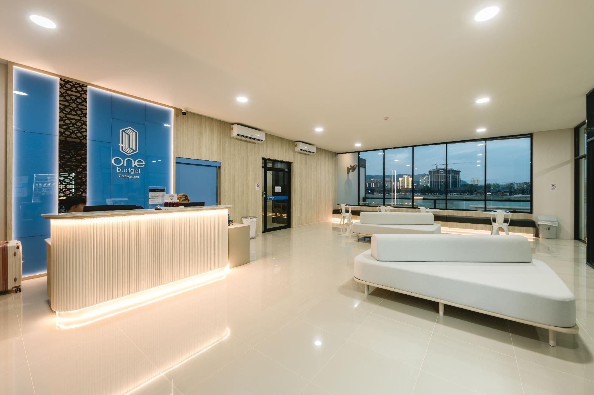 A modern reception area with a blue wall, a reception desk, and a seating area with white sofas.