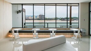 Une pièce moderne avec de grandes fenêtres, un canapé blanc et deux tables blanches.