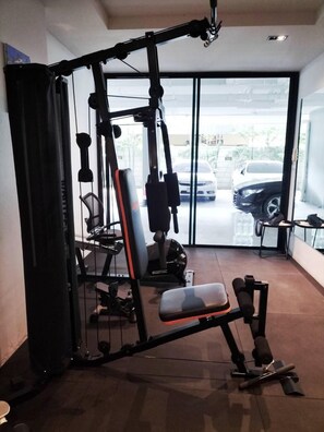 Une salle de sport équipée d’un support à squats, d’un banc de développé couché et de divers appareils de musculation.
