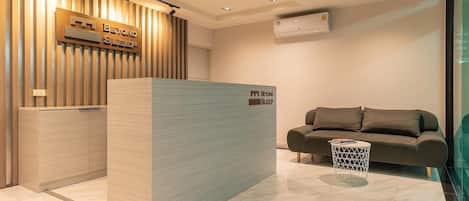 A modern reception area with a wooden panel wall, a reception desk, a sofa, and a small round table.