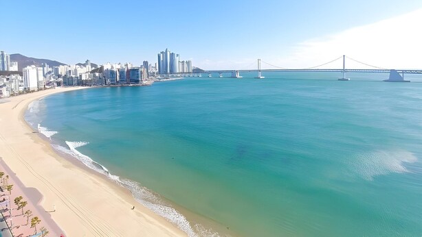 A coastal cityscape with a prominent bridge, sandy beaches, and a clear blue sea. - Elmomento Gwangan Hotel Residence (Busan)
