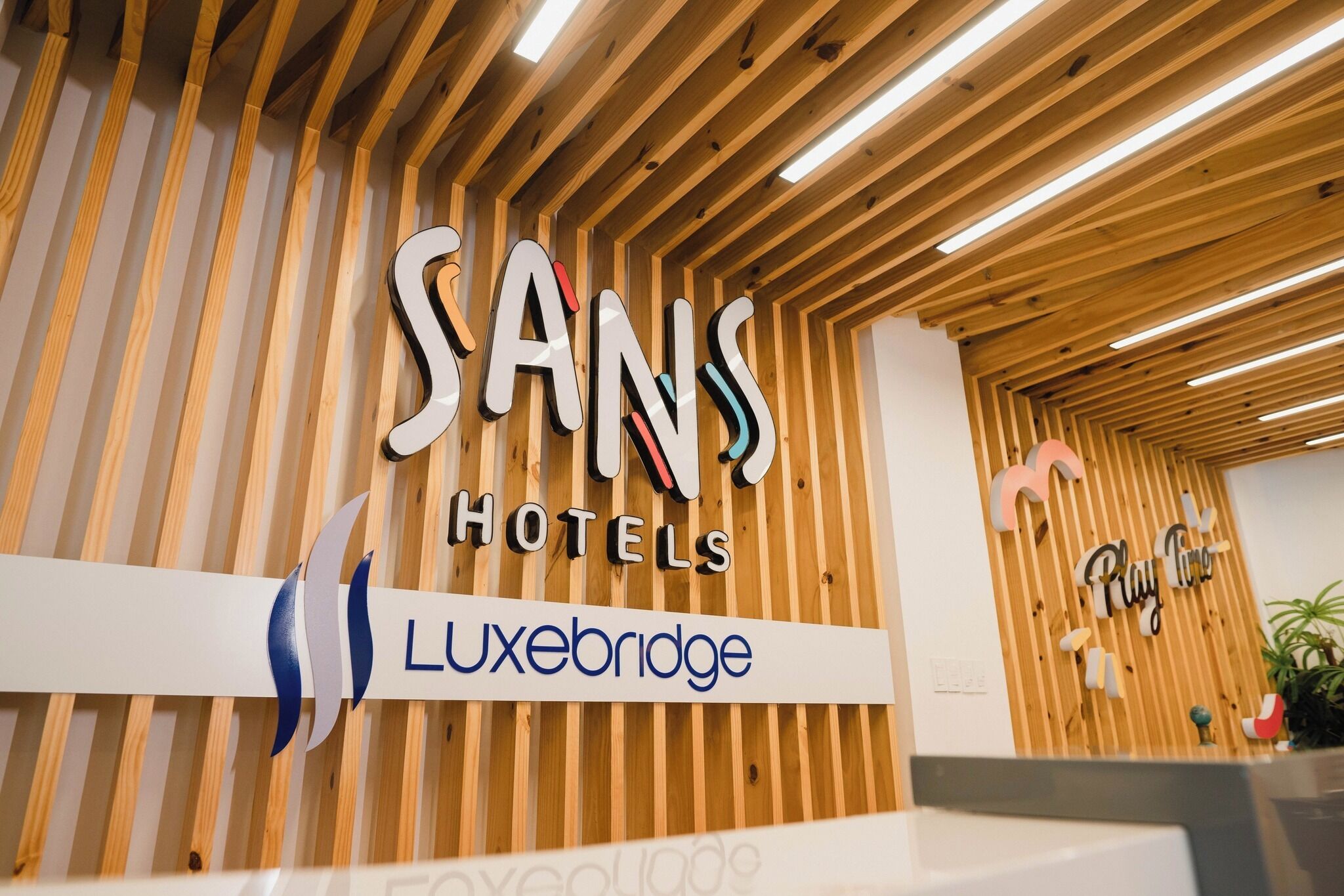 A reception desk with a sign for Sans Hotels and Luxebridge.