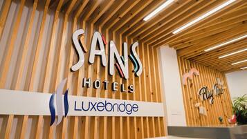 A reception desk with a sign for Sans Hotels and Luxebridge.