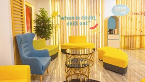 A modern interior with yellow and blue furniture, a glass coffee table, and a sign offering coffee. - Luxebridge Hotel (Davao)