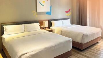 Una habitación de hotel con dos camas, una mesita de noche con lámpara y una pared decorada con arte abstracto.