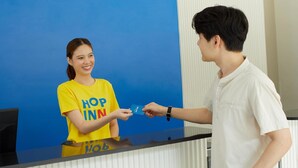 Un comptoir d’accueil d’hôtel avec un fond bleu et l’inscription « HOP INN » bien visible.