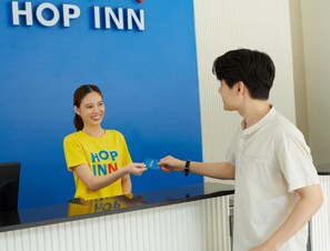 Mostrador de recepción de un hotel con fondo azul y el texto "HOP INN" visible.