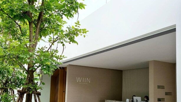 A modern hotel lobby with a reception desk, seating area, and a tree. - Wiin Phetchaburi (Phetchaburi)