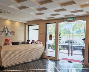 Een hotel receptiebalie met een incheck counter, een klok en een bord met de naam van het hotel.