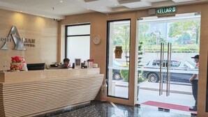 Un comptoir d’accueil d’hôtel avec un guichet d’enregistrement, une horloge et une enseigne indiquant le nom de l’hôtel.