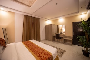 Ein Hotelzimmer mit einem Bett, einem Schreibtisch, einem Spiegel, einem Kleiderschrank und einer Tür.