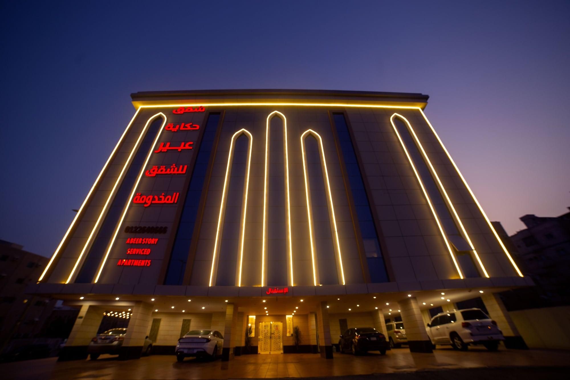 Un hotel con fachada moderna, con líneas verticales iluminadas y señalización árabe.