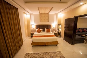 Una habitación de hotel con una cama grande, lámparas de noche, un espejo, un sofá y una puerta.
