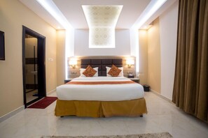 Habitación de hotel con una cama grande, cabecera con iluminación integrada, alfombra roja y vista al cielo a través de un tragaluz.