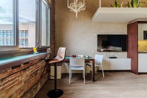 Uma área de jantar moderna com parede de tijolos, uma janela grande e um lustre.