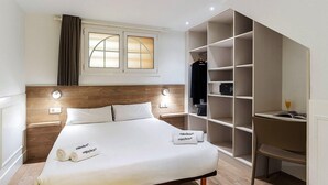 Habitació d'hotel amb un llit, un armari i una finestra amb cortines.