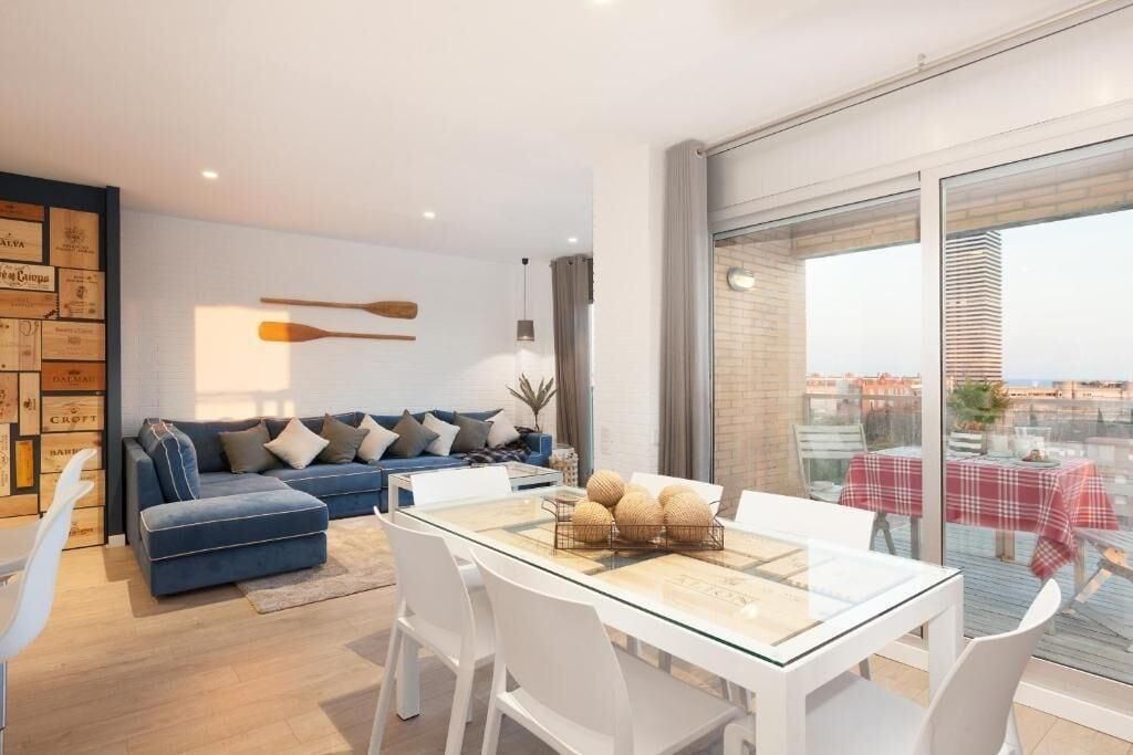Ein modernes Wohnzimmer mit einem Glastisch, einem blauen Sofa und Blick auf die Stadt durch große Fenster.