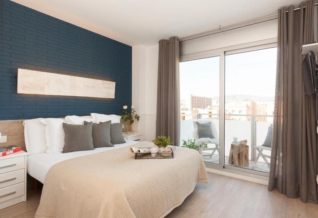 Ein modernes Schlafzimmer mit einem großen Bett, Blick auf die Stadt durch eine Schiebetür und einer blauen Akzentwand.