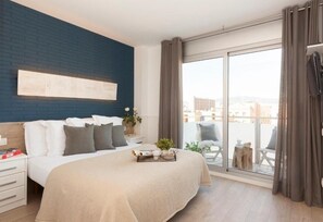 Un dormitorio moderno con una cama grande, vistas de la ciudad a través de un ventanal corredero y una pared de acento azul.