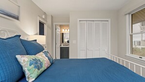 A bedroom with a bed, a nightstand, a lamp, a closet, and a window. - Luxury Lakefront Living | New vacation rental (Spring Lake)