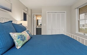 A bedroom with a bed, a nightstand, a lamp, a closet, and a window. - Luxury Lakefront Living | New vacation rental (Spring Lake)
