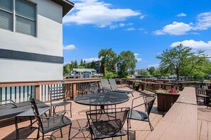 An outdoor patio area with tables and chairs, a wooden deck, and a view of surrounding buildings and trees. - Updated condo with water views-  perfect location (South Haven)