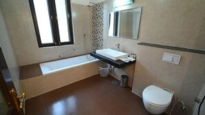 Ein Badezimmer mit Badewanne, Waschbecken, Toilette und einem Fenster.