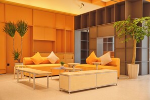 Een moderne lobby met een zithoek, een bijzettafeltje en een potplant.