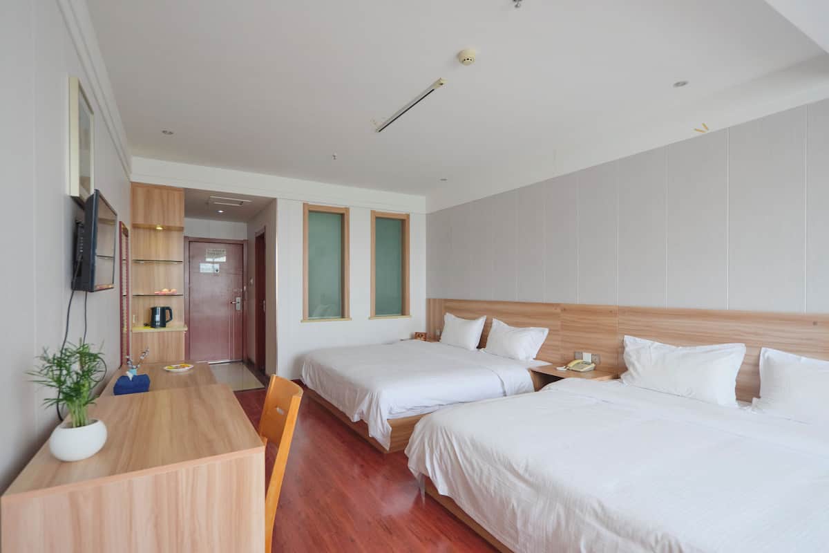 Une chambre d’hôtel avec deux lits, un bureau en bois, une télévision et une petite kitchenette.