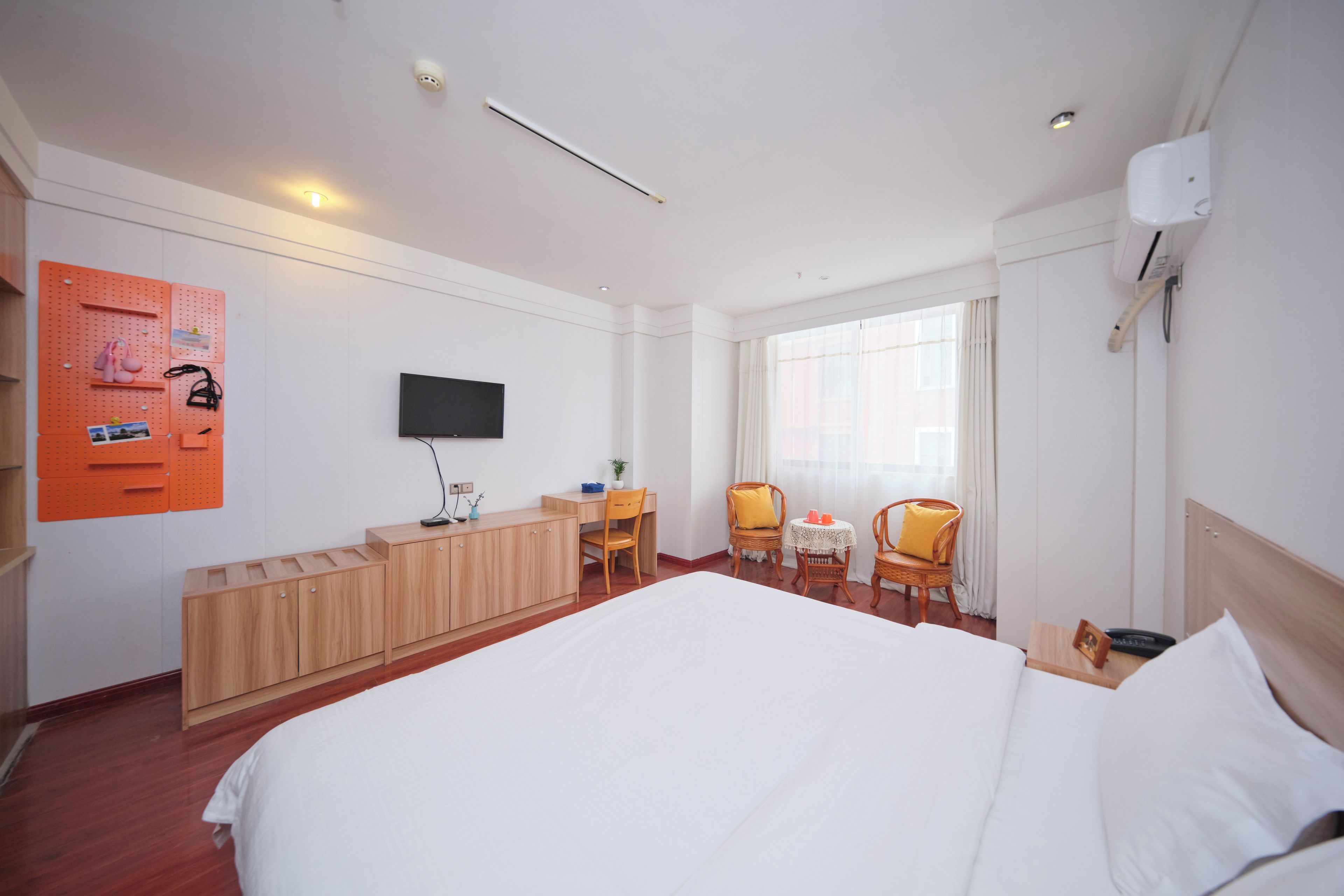 Habitación de hotel con una cama grande, un escritorio, una silla, una mesita y un televisor en la pared.