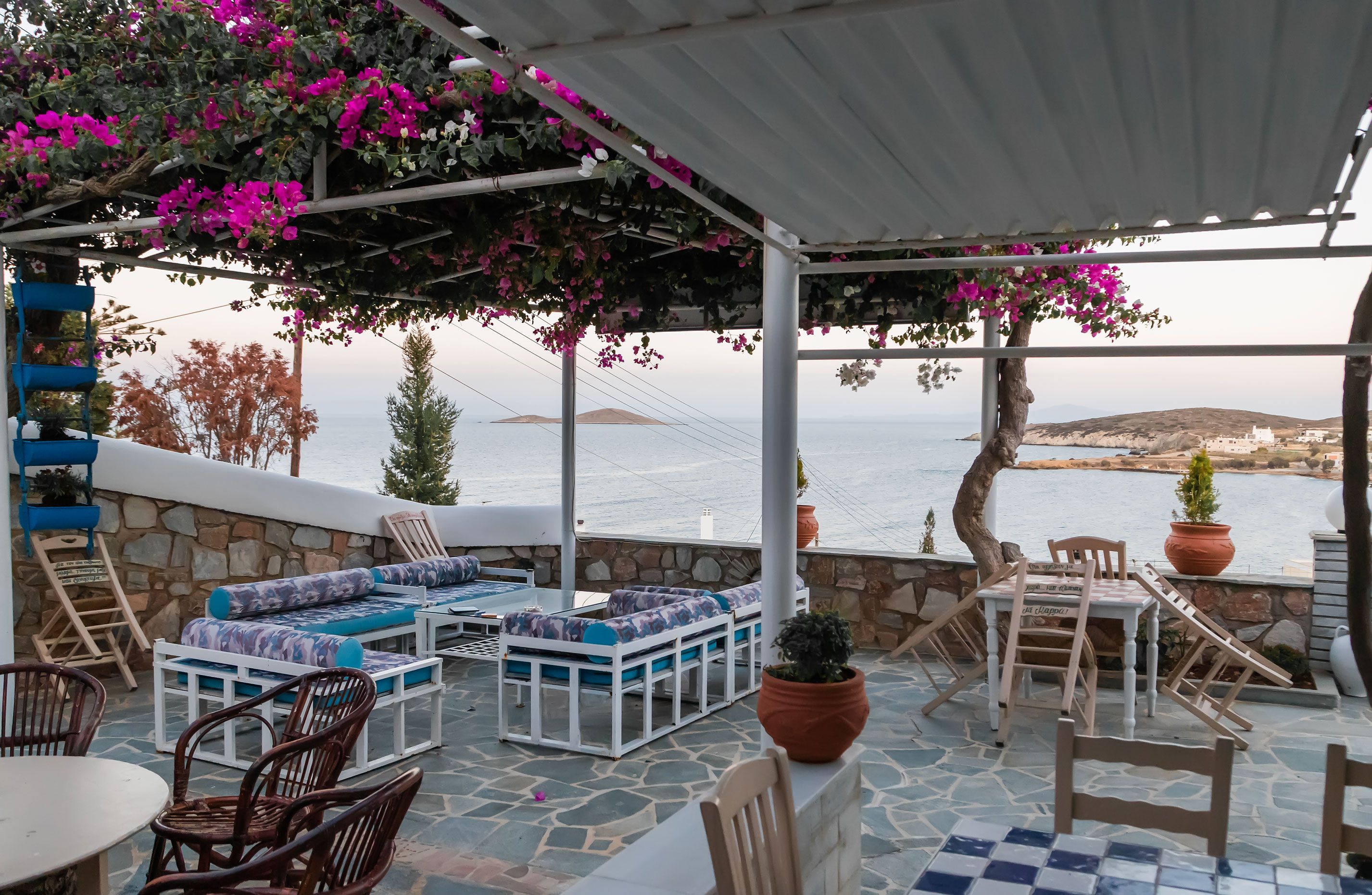 An outdoor seating area with stone walls, white furniture, and potted plants.