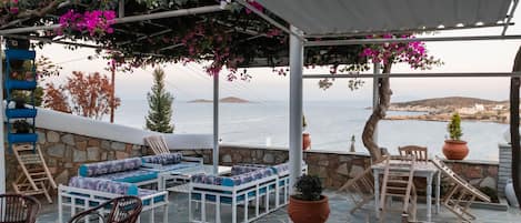 An outdoor seating area with stone walls, white furniture, and potted plants.