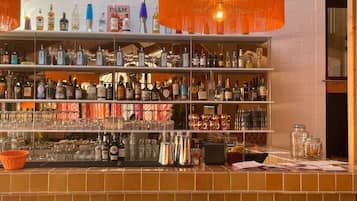 Un espace bar avec des étagères remplies de bouteilles d’alcool, des verres et un comptoir avec des tabourets.