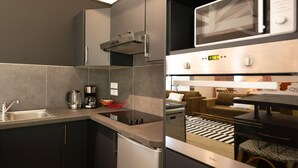 A modern kitchen with a built-in microwave, a coffee maker, and a kettle. - La Baignoire Hotel du Golf Lacanau (Lacanau)