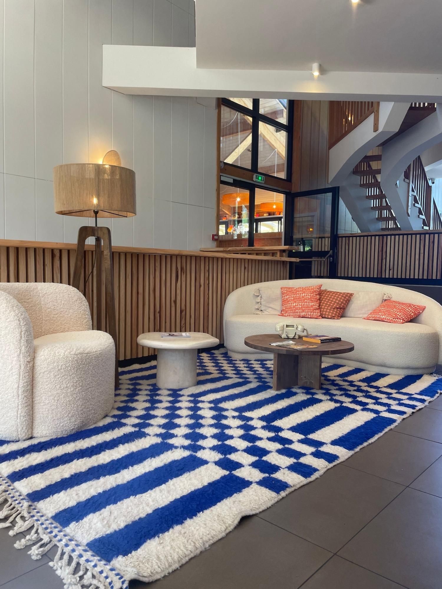 A modern lobby with a sofa, chairs, a coffee table, and a patterned rug.