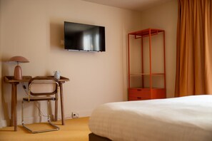 A hotel room with a bed, a desk with a chair, a television mounted on the wall, and a red storage unit. - La Baignoire Hotel du Golf Lacanau (Lacanau)