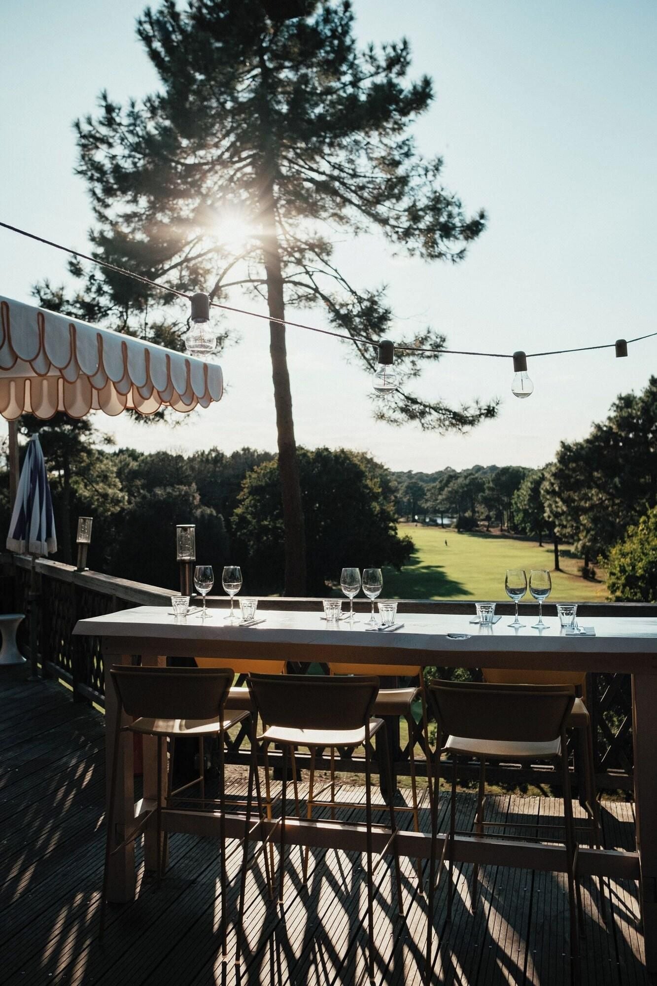 An outdoor dining area with a table set for four, overlooking a golf course.