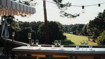 An outdoor dining area with a table set for four, overlooking a golf course.
