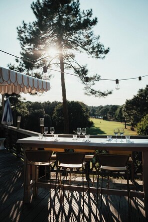 An outdoor dining area with a table set for four, overlooking a golf course. - La Baignoire Hotel du Golf Lacanau (Lacanau)