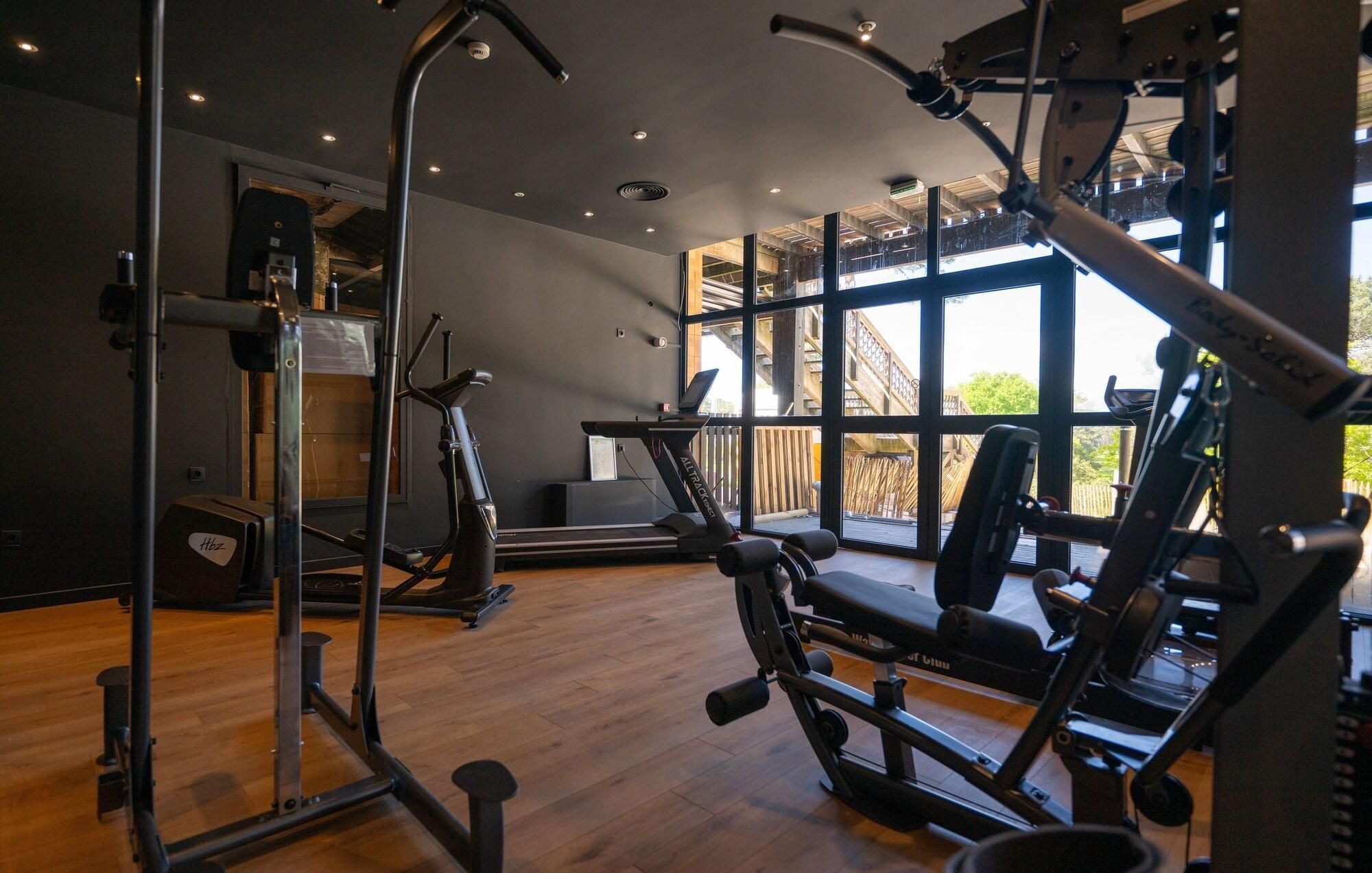 Une salle de sport équipée de matériel d’exercice, dotée de grandes fenêtres et d’un plancher en bois.