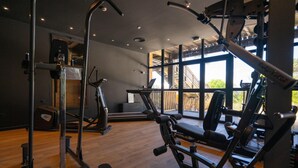 A gym with exercise equipment, large windows, and a wooden floor. - La Baignoire Hotel du Golf Lacanau (Lacanau)