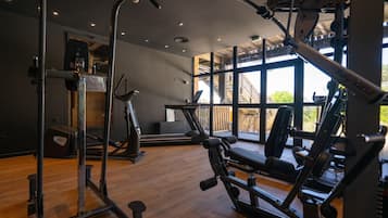 Une salle de sport équipée de matériel d’exercice, dotée de grandes fenêtres et d’un plancher en bois.