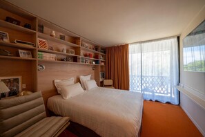 A hotel room with a large bed, a desk, a chair, and a bookshelf. - La Baignoire Hotel du Golf Lacanau (Lacanau)