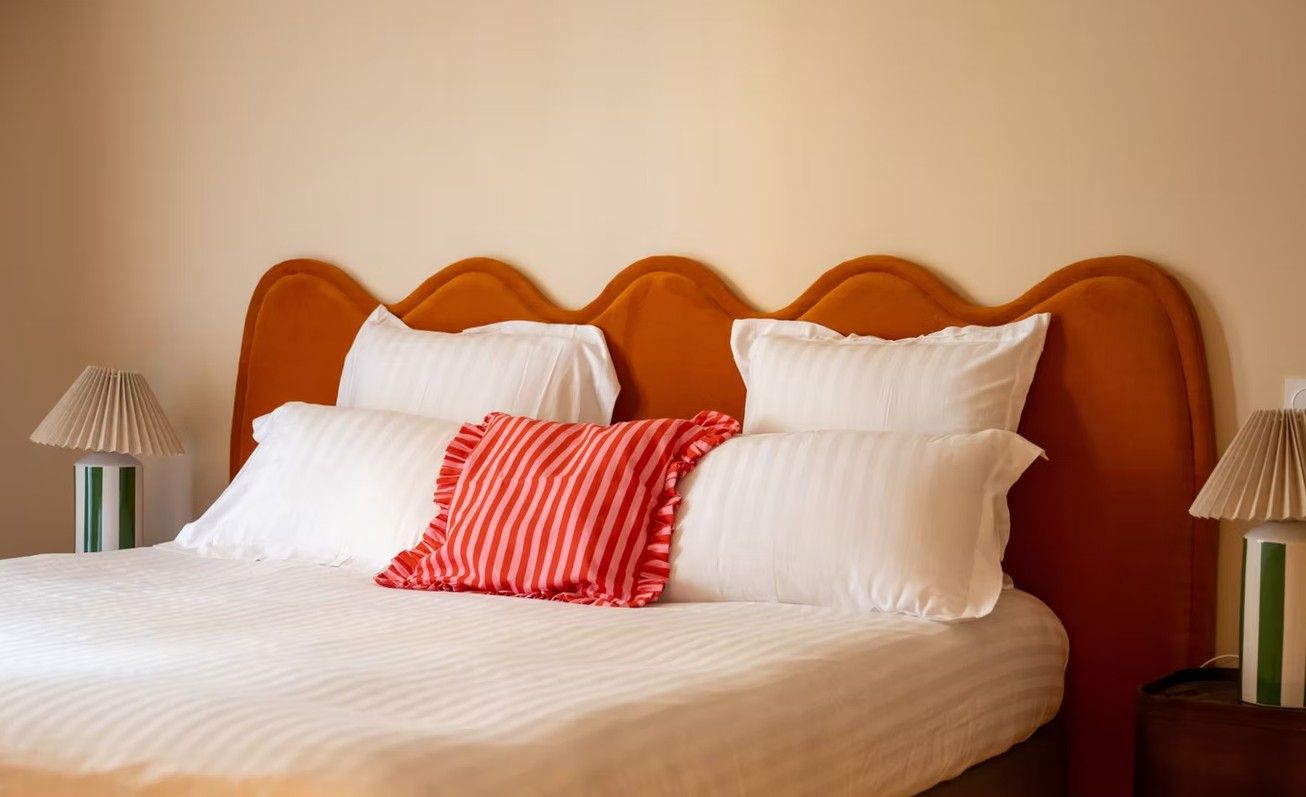 A bed with a wooden headboard, white bedding, and striped pillows.
