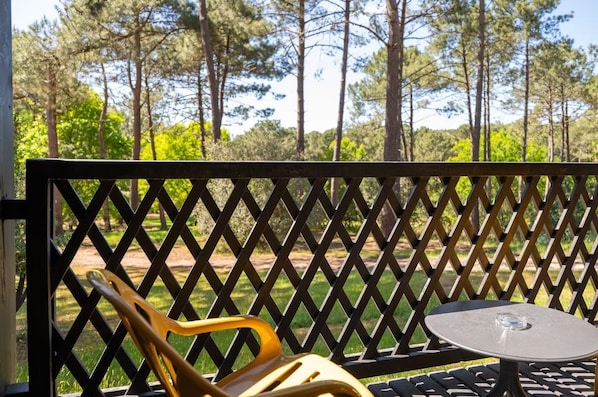 A patio with a lattice fence, a round table, and a yellow chair. - La Baignoire Hotel du Golf Lacanau (Lacanau)