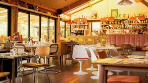 Un restaurant au décor intérieur en bois, doté de grandes fenêtres et d’un bar où sont exposées différentes bouteilles.