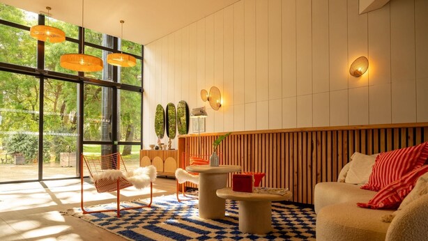 Un salon moderne doté d’une grande fenêtre, d’un mur avec des lambris en bois et d’un tapis à carreaux.