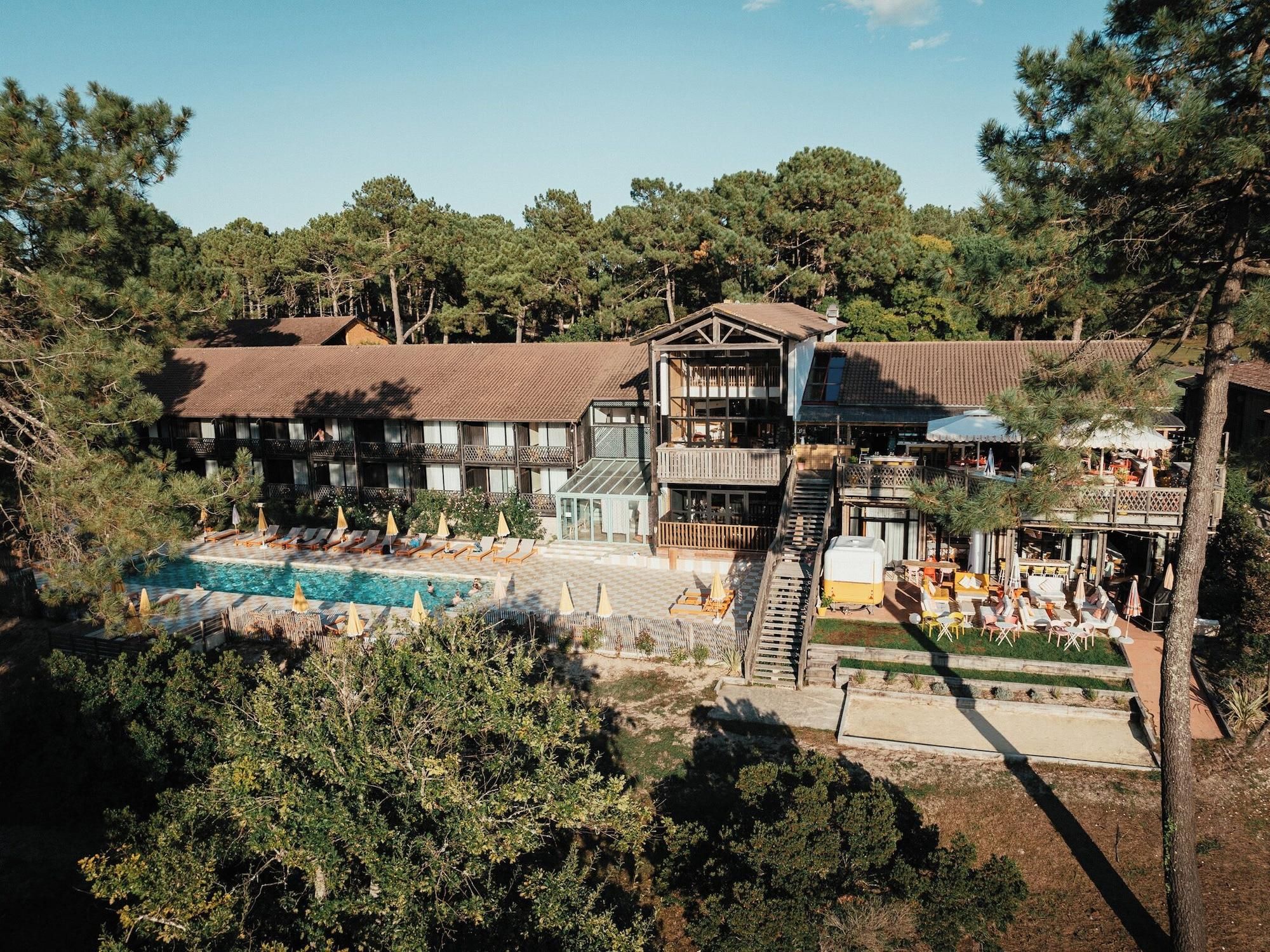 A resort with a swimming pool, outdoor seating, and a building with multiple balconies.