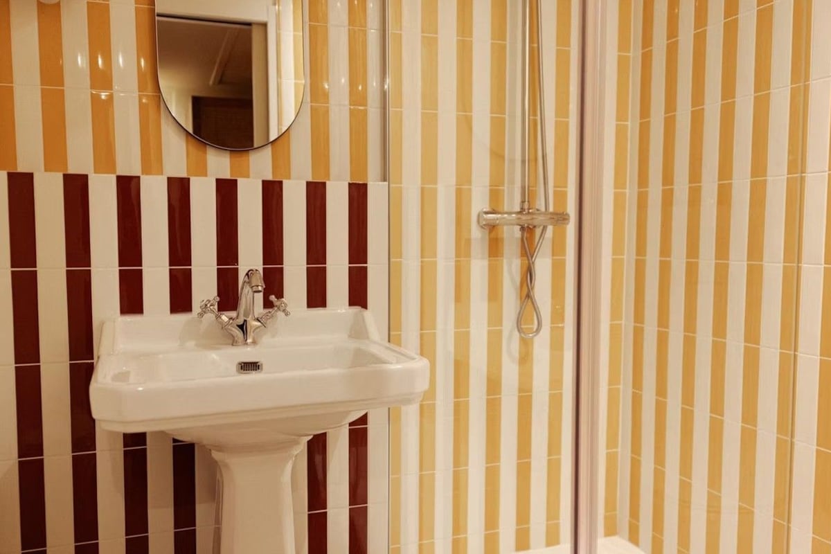 A bathroom with a white pedestal sink, a mirror above it, and a shower with a glass door.